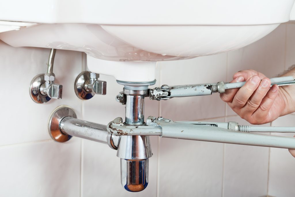 a professional doing some drain repair on a home's sink