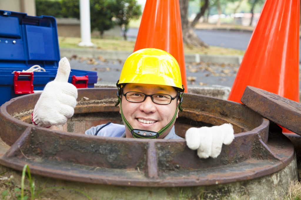 a professional working on sewer repair giving a thumbs up