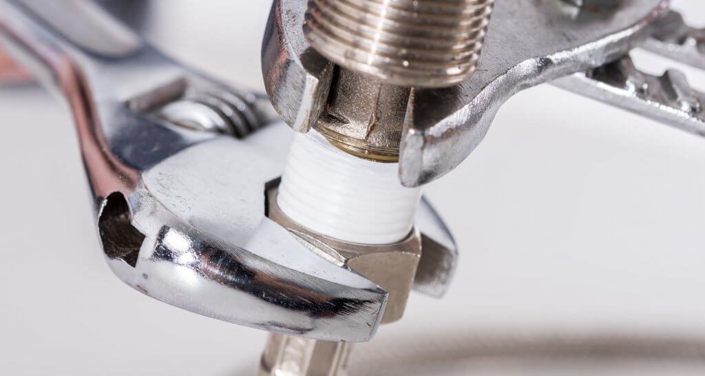 a wrench tightening a nut under a sink